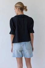 Load image into Gallery viewer, Person wearing a black blouse and light blue shorts against a plain background