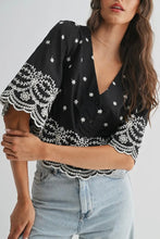 Load image into Gallery viewer, Woman wearing a black blouse with white lace details and light blue jeans on a plain background
