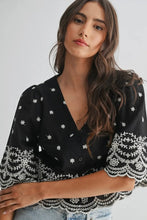 Load image into Gallery viewer, Woman wearing a black blouse with white floral patterns on a plain background