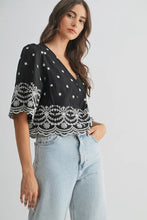 Load image into Gallery viewer, Woman wearing a black top with white lace details and light blue jeans on a gray background