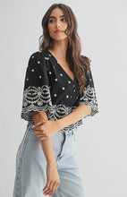 Load image into Gallery viewer, Woman wearing a black top with white patterns and light blue jeans on a gray background