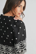 Load image into Gallery viewer, Woman wearing a black top with white floral patterns on a plain background