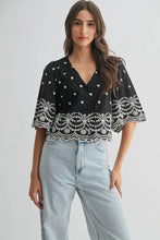 Load image into Gallery viewer, Woman wearing a black top with white lace details and light blue jeans on a plain background