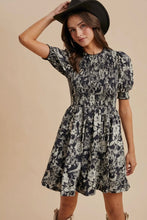 Load image into Gallery viewer, Woman wearing a floral dress and black hat against a beige background