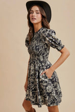 Load image into Gallery viewer, Woman wearing a floral dress and black hat against a beige background