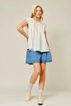 Load image into Gallery viewer, Woman wearing a white top, blue shorts, and beige shoes on a plain background