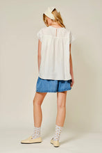 Load image into Gallery viewer, Young girl wearing a white blouse and blue shorts on a plain background