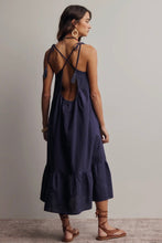 Load image into Gallery viewer, Woman wearing a navy blue dress with criss-cross straps and tiered skirt on a plain background