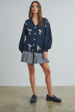 Load image into Gallery viewer, Woman wearing a navy cardigan with white details and a checkered skirt on a plain background