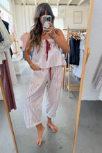 Load image into Gallery viewer, Person wearing a striped outfit taking a mirror selfie in a clothing store.