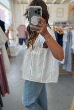 Load image into Gallery viewer, Person taking a mirror selfie wearing a white top and blue jeans in a clothing store.