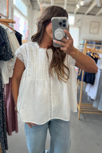 Load image into Gallery viewer, Woman taking a mirror selfie wearing a white blouse and blue jeans in a clothing store.