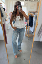 Load image into Gallery viewer, Woman taking a mirror selfie wearing a white top and blue jeans in a clothing store.