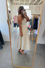 Load image into Gallery viewer, Woman in a beige dress standing in front of a mirror in a clothing store.