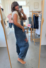 Load image into Gallery viewer, Person wearing denim overalls taking a mirror selfie in a clothing store.