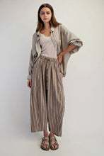 Load image into Gallery viewer, Woman wearing a beige shirt and striped pants on a white background