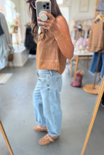 Load image into Gallery viewer, Person wearing a brown top and light blue jeans in a clothing store.