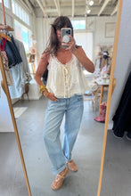 Load image into Gallery viewer, Woman taking a mirror selfie wearing a white lace top and light blue jeans in a store.