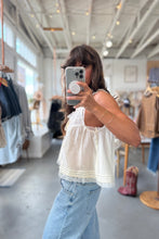 Load image into Gallery viewer, Person taking a mirror selfie in a clothing store wearing a white top and blue jeans.