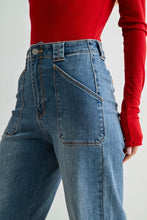 Load image into Gallery viewer, Close-up of a person wearing high-waisted blue jeans with a red ribbed long-sleeve top, showing the back pocket and waistband details against a light gray studio background.