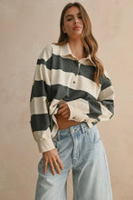 Load image into Gallery viewer, Woman wearing a black and white striped shirt with light blue jeans on a beige background