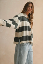 Load image into Gallery viewer, Woman wearing a black and white striped shirt with light blue jeans against a beige background