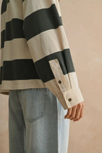 Load image into Gallery viewer, Person wearing a black and beige striped shirt with rolled-up sleeves against a beige background