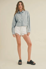 Load image into Gallery viewer, Woman wearing a light blue denim jacket and white shorts on a beige background