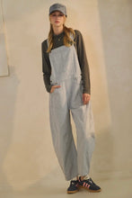 Load image into Gallery viewer, Person wearing light blue overalls and a dark shirt with a neutral background