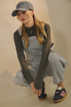 Load image into Gallery viewer, Person wearing a gray cap, dark long-sleeve shirt, gray overalls, and navy sneakers on a beige background