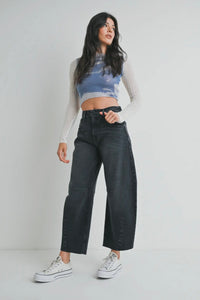 Woman wearing a tie-dye crop top and black jeans on a plain background