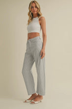 Load image into Gallery viewer, Woman wearing a white sleeveless top and light gray jeans on a beige background