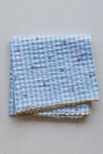 Load image into Gallery viewer, Folded blue checkered fabric with floral patterns on a gray background
