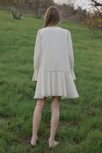Load image into Gallery viewer, Woman wearing a light-colored dress standing in a grassy field.