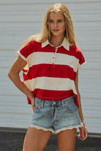 Load image into Gallery viewer, A woman modeling a red and off-white striped short-sleeve polo shirt with denim shorts against a light gray corrugated metal background.