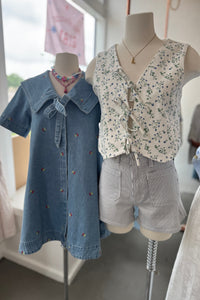 Denim shirt and floral vest on mannequins with a blurred indoor background