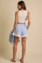 Load image into Gallery viewer, Woman wearing a white sleeveless top and blue checkered shorts on a beige background
