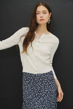 Load image into Gallery viewer, Woman wearing a white blouse with lace details and a floral skirt against a black background