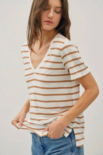 Woman wearing a white and brown striped shirt with blue jeans on a plain background
