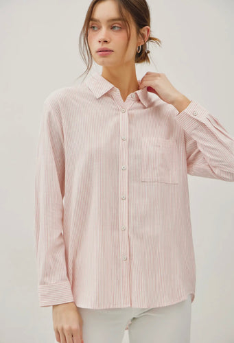 Woman wearing a pink striped shirt against a plain background