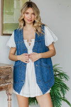 Load image into Gallery viewer, Woman wearing a denim vest over a white dress with a plant and wooden table in the background