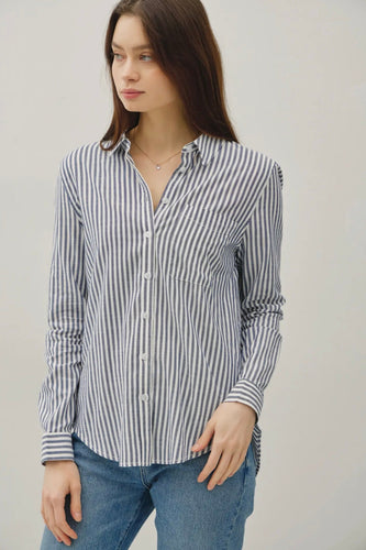 Woman wearing a striped shirt and jeans against a plain background