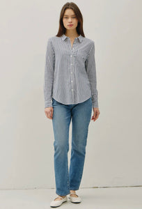 Woman wearing a striped shirt and blue jeans against a plain background