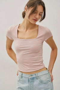 Woman wearing a pink striped top and light blue jeans against a plain background