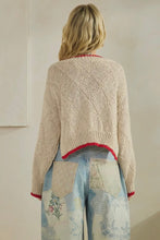 Load image into Gallery viewer, Person wearing a beige knitted cardigan with red trim, standing against a plain background.