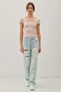 Woman wearing a pink top and light blue jeans on a white background