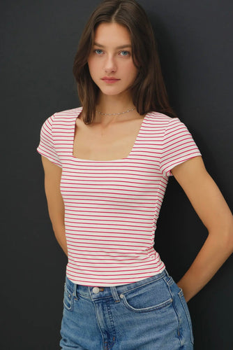Woman wearing a red and white striped shirt and blue jeans against a black background
