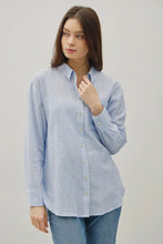 Load image into Gallery viewer, Woman wearing a light blue striped shirt and jeans on a plain background