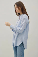 Load image into Gallery viewer, Woman wearing a light blue striped shirt and jeans against a plain background