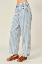 Load image into Gallery viewer, A person wearing light blue and white vertically striped wide-leg cropped jeans with brown leather loafers, shown from the waist down against a plain beige studio background.